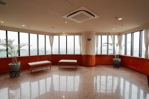 A spacious room with large windows, a bench, and a potted plant. - Landis Inn Lotung (Luodong)