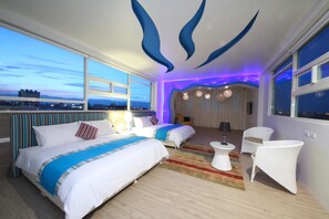 A modern hotel room with a large bed, a smaller bed, and a seating area with a view of the cityscape. - Tsaihang Fashion B nd B (Luodong)