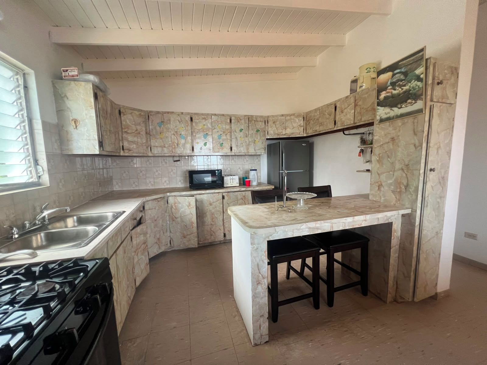 A kitchen with a curved island, a stove, a refrigerator, and a microwave.
