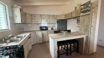A kitchen with a curved island, a stove, a refrigerator, and a microwave.