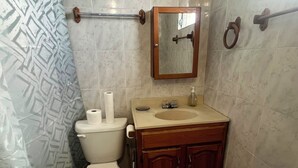 Et badeværelse med toilet, vask, spejl og håndklædestang.