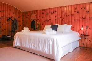 Un dormitorio con una cama grande, una pared de madera, un espejo y una pequeña mesa con lámpara.
