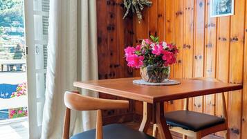 Una habitación con paneles de madera, una mesa y sillas, una ventana con cortinas y un cuadro colgado en la pared.