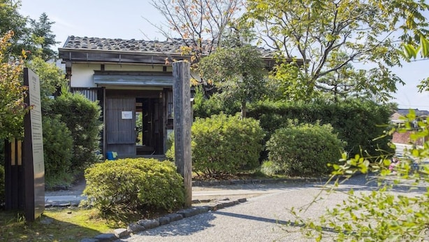 A traditional Japanese building with a tiled roof, surrounded by well-maintained greenery and a gravel path leading to the entrance. - Kanazawa Central Hotel Annex (Kanazawa)