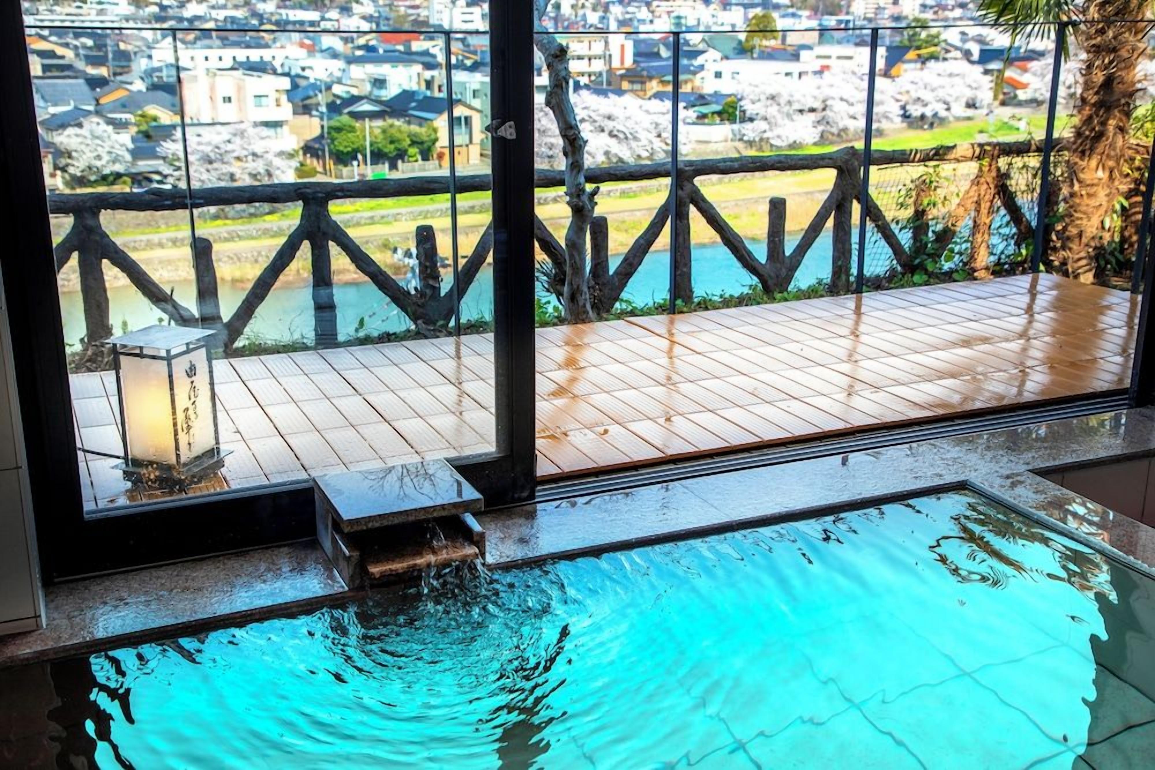 An indoor swimming pool with a wooden deck and a view of a residential area.