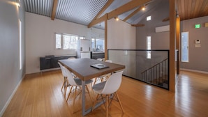 A modern interior with a dining area, kitchen, and staircase. - Powdersuites (Hakuba)