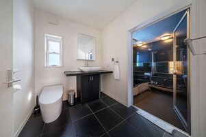Un baño moderno con inodoro, lavamanos y zona de ducha.