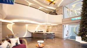 A modern hotel lobby with a reception desk, seating area, and a Christmas tree. - Yanold Fashion Spring House (Jiaoxi)