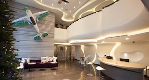 A modern hotel lobby with a curved reception desk, a seating area with a sofa and chairs, and a Christmas tree. - Yanold Fashion Spring House (Jiaoxi)