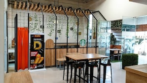 Interior de café com mesas e cadeiras de madeira, logotipo da Starbucks e parede com jardim vertical.