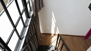 Uma escadaria com corrimão de metal, conduzindo a um patamar com vista para o exterior.