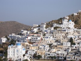 Un asentamiento en una ladera densamente poblado, con edificios blancos, algunos con detalles azules, y una iglesia destacada con una cúpula azul.