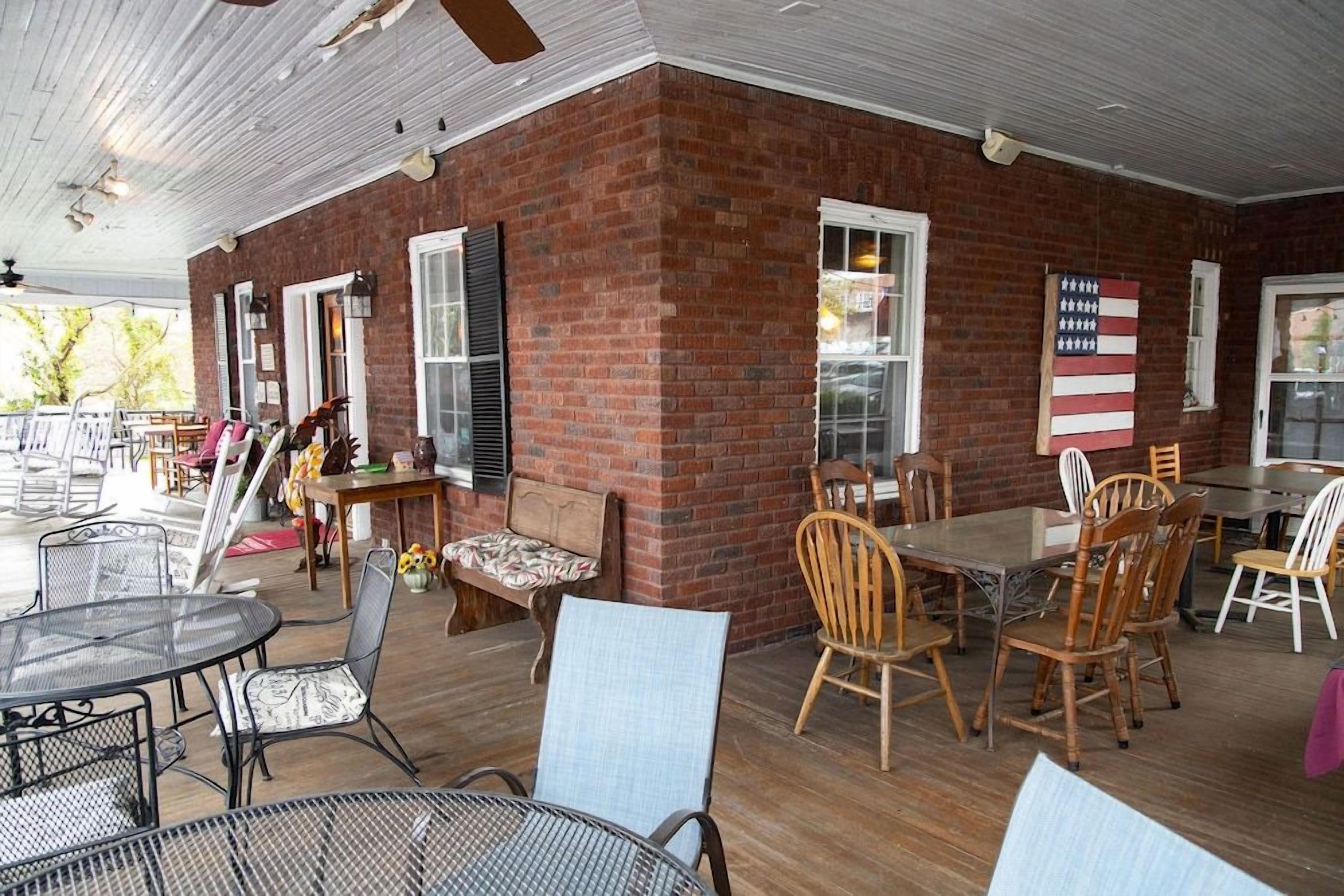 An outdoor patio with brick walls, metal tables, and wooden chairs.