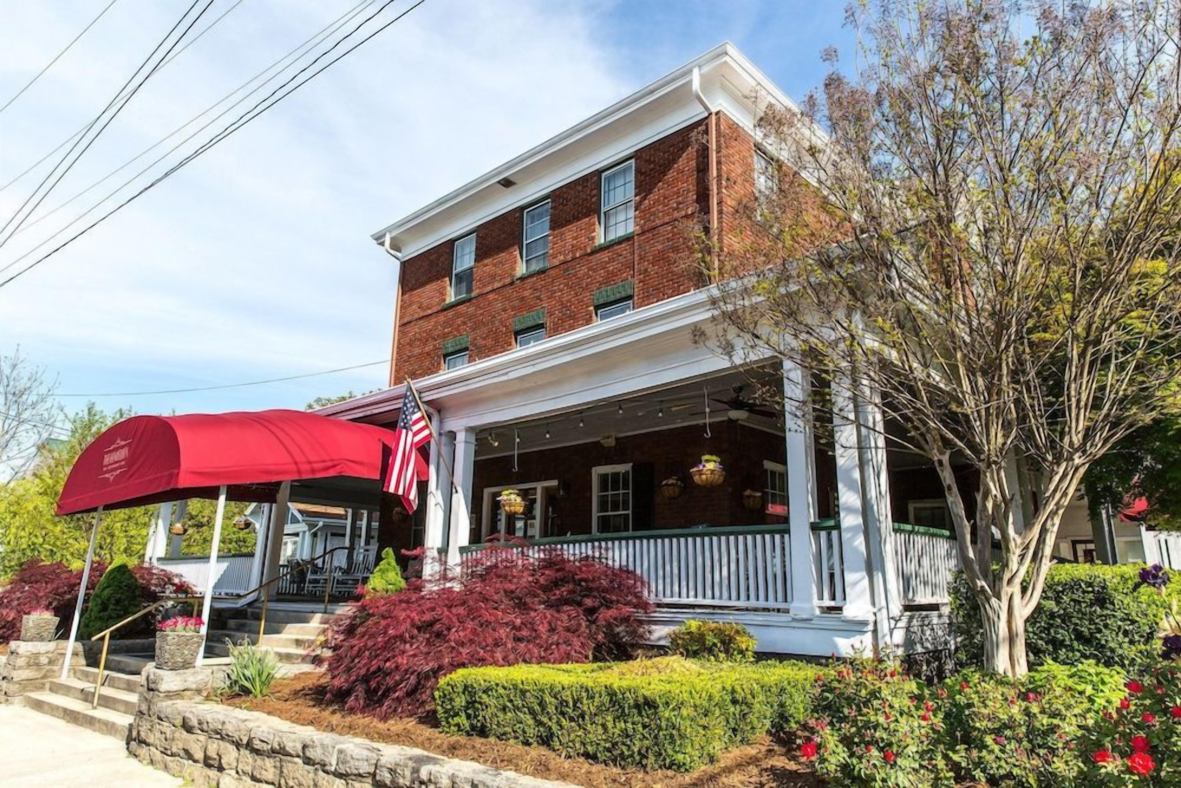 A two-story brick building with a white porch and a red awning.