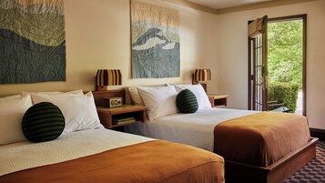 A hotel room with two beds, a large window, and artwork on the walls.