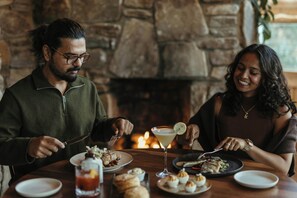 A couple dining at a table with a stone fireplace in the background. - Highlands Inn Lodge Formerly Hampton Inn Highlands (Highlands)