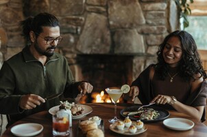 A couple dining at a table with a stone fireplace in the background.
