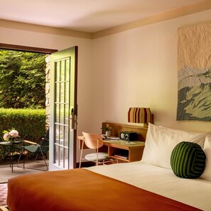 A bedroom with a bed, a desk, a chair, and a radio. There is a door leading to an outdoor area with a table and chairs. - Highlands Inn Lodge Formerly Hampton Inn Highlands (Highlands)