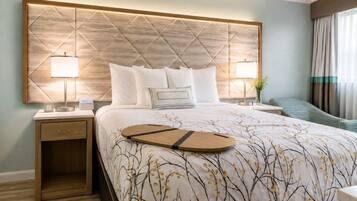 Habitación de hotel con una cama grande, dos mesitas de noche y vistas al exterior.