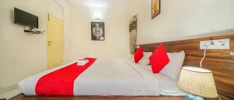 Una habitación de hotel con una cama, una lámpara de noche, un televisor y una puerta.