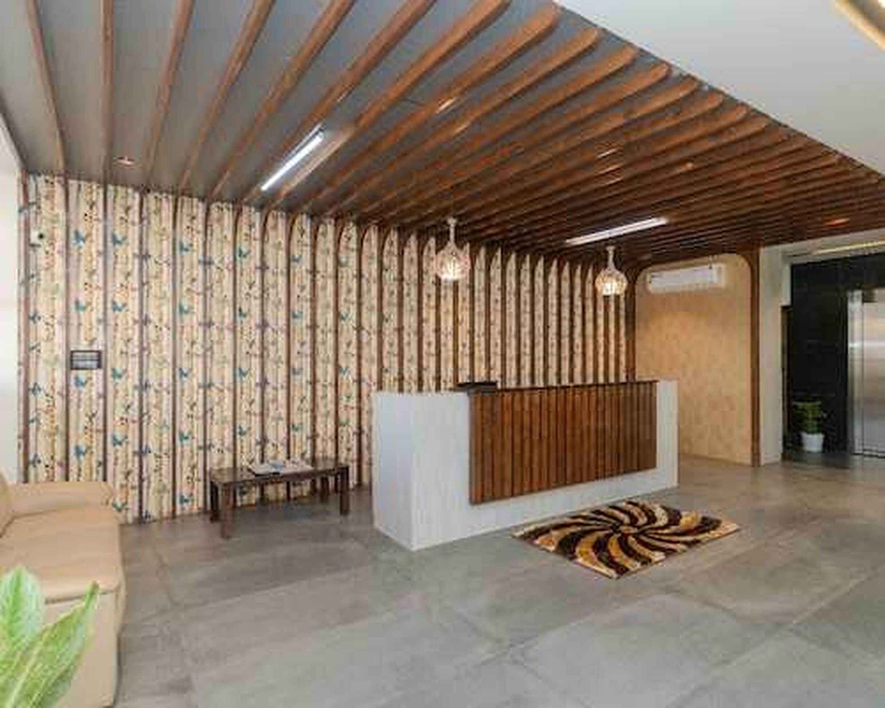Un'area reception con una scrivania in legno, tende decorate, un tappeto a motivi e un lampadario.