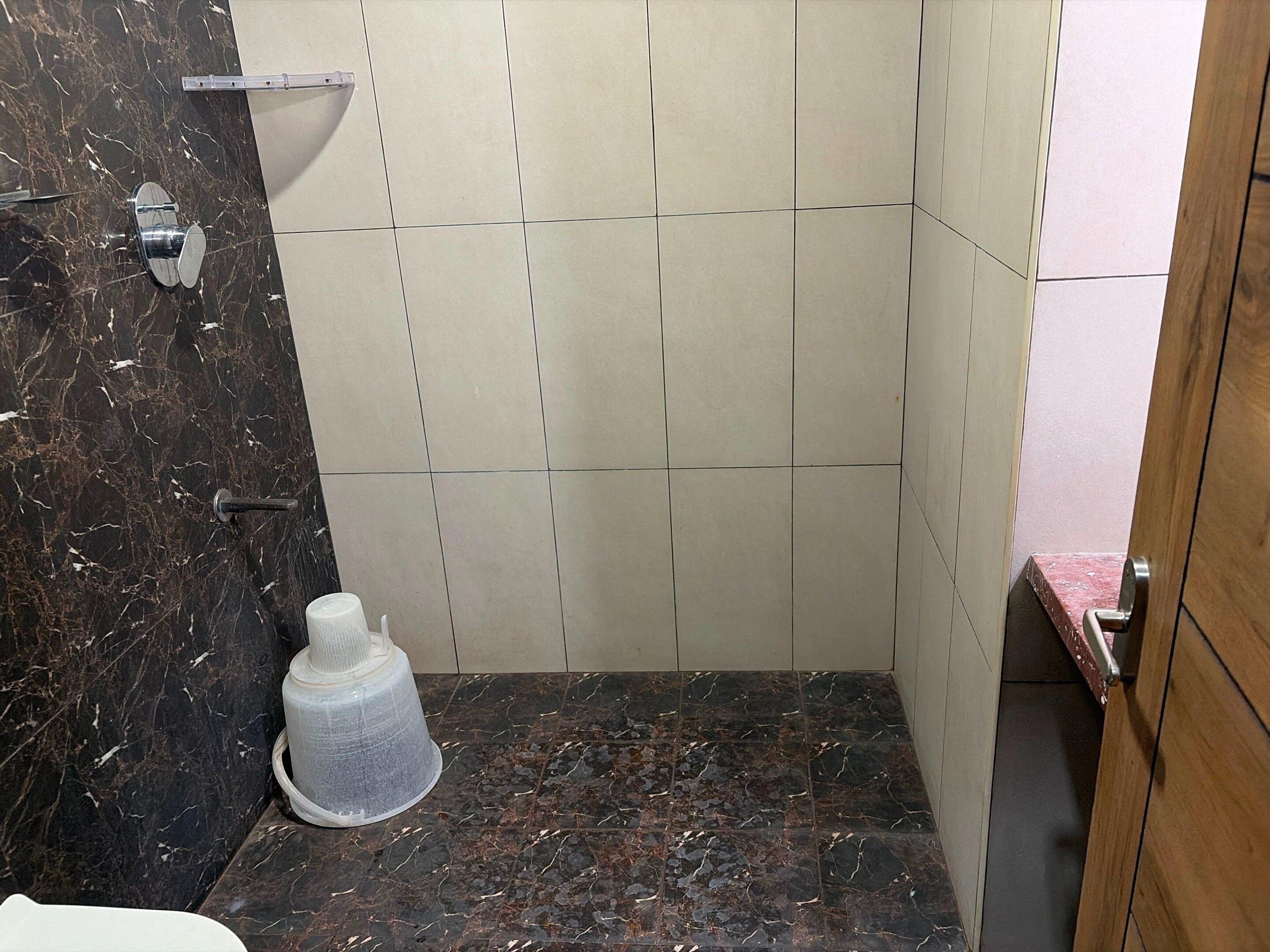 Een badkamer met een marmeren wand, een douche en een toilet.