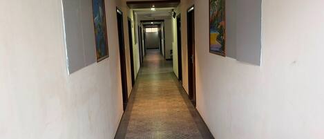A long, narrow hallway with patterned flooring and doors on both sides.