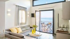 Un interior moderno con un sofá, una mesa de comedor y vistas al mar a través de una puerta abierta.