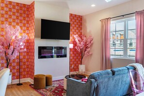 Een moderne woonkamer met een flatscreen televisie, een bank, een salontafel en decoratieve kersenbomen.