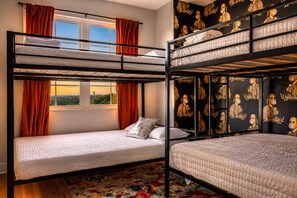 Una habitación con literas, una ventana con cortinas y un papel tapiz con un diseño repetido.