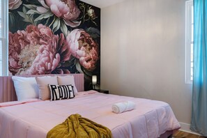 A bedroom with a large floral mural, a bed with pink bedding, and a window with curtains. - Double Feature - Group Stay w/ Rooftop Hot tubs (Nashville)