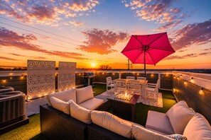 An outdoor seating area with a red umbrella, white chairs, and a grill. - Double Feature - Group Stay w/ Rooftop Hot tubs (Nashville)