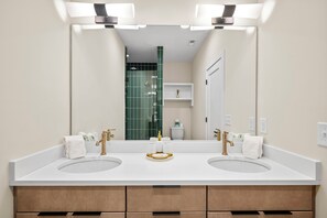 Un baño con dos lavamanos, un espejo grande y una zona de ducha.