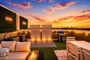 Terraza en la azotea con parrilla, zona de estar y paneles decorativos.