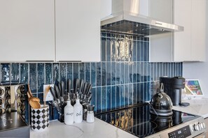 Een moderne keuken met een zwart-wit betegelde spatwand, roestvrijstalen apparatuur en netjes opgeruimde keukengerei.