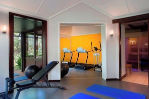 Une salle de sport équipée de matériel d’exercice, notamment des tapis de course et un banc de musculation.