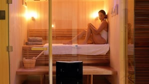 A sauna room with a wooden bench, a towel, and a heater. - Le Meridien Ile des Pins (L'Île-des-Pins)