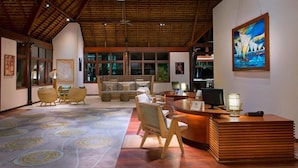 A spacious lobby with a reception desk, seating area, and artwork on the walls. - Le Meridien Ile des Pins (L'Île-des-Pins)
