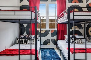 Ein Zimmer mit Etagenbetten, einem Fenster und einer Wand mit Muster.
