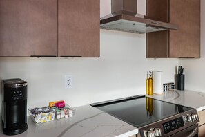 A kitchen with a built-in stove, a coffee maker, and a spice rack. - The Vivid - Rooftop Hot Tub/Game Room/Sleeps 16 (Nashville)
