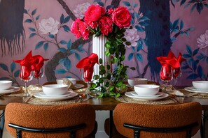 A dining table set with white plates, bowls, and glasses, adorned with red napkins and a floral centerpiece. - The Vivid - Rooftop Hot Tub/Game Room/Sleeps 16 (Nashville)