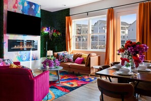 A modern living room with a sofa, a coffee table, and a dining area set for a meal. - Velvet Escape - Groups/Game Room/Rooftop Hot Tub (Nashville)