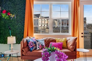 A cozy living room with a sofa, a small table, and a window with curtains. - Velvet Escape - Groups/Game Room/Rooftop Hot Tub (Nashville)