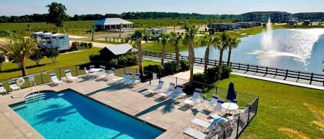 A swimming pool with lounge chairs and a fountain.