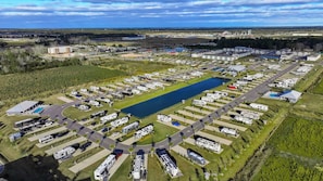 An aerial view of a campground with RVs, a swimming pool, and a lake.