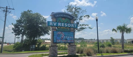 Une enseigne indiquant le « Grand Riviera RV Resort », avec un ciel dégagé et des palmiers en arriÚre-plan.