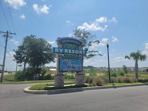 A sign for Grand Riviera RV Resort with a clear sky and palm trees in the background. - Relaxing RV resort in Foley Alabama LOT 78 with 3 pools 1 heated year round (Foley)
