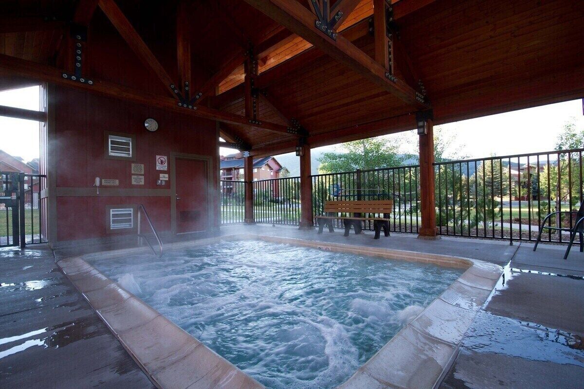 Un jacuzzi bajo un pabellón de madera con un banco y una valla de fondo.