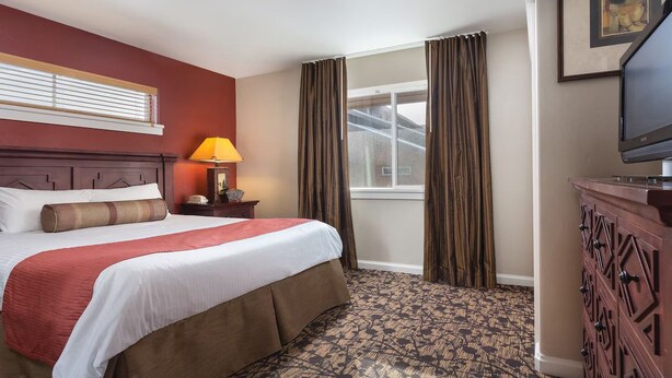 A hotel room with a bed, a nightstand, a lamp, a television, and a window with curtains. - Rare find- Spacious 2 bdrm condo during President's Day in Steamboat Springs (Steamboat Springs)