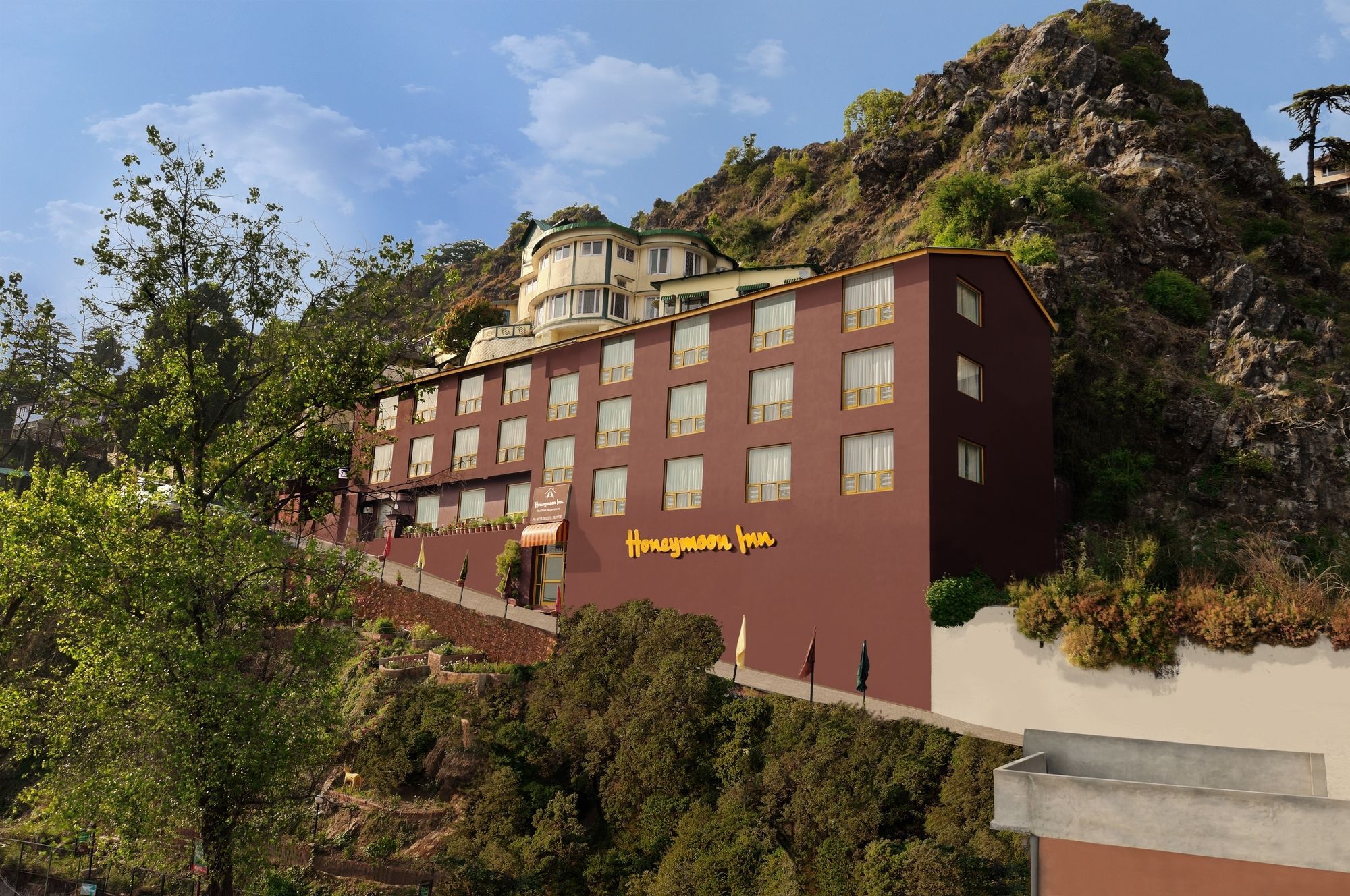 Un hotel de varios pisos, con una entrada destacada y ubicación en una colina.